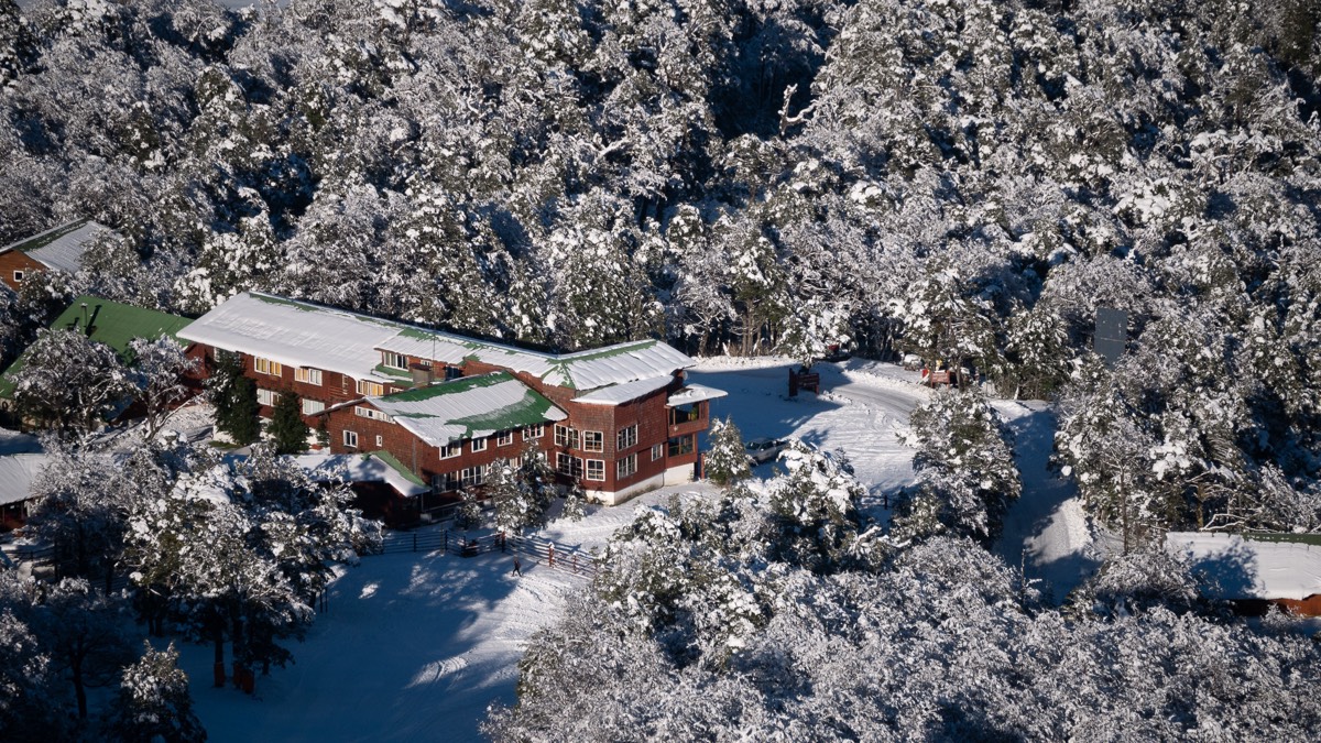 Refugio de Antillanca cubierto de nieve entre el bosque, centro de esquí en la cordillera de Puyehue