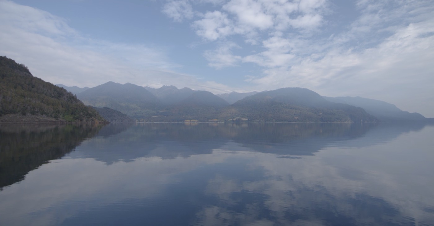 Aguas calmas del Lago Rupanco con las montañas reflejadas al amanecer, ideal para la pesca
