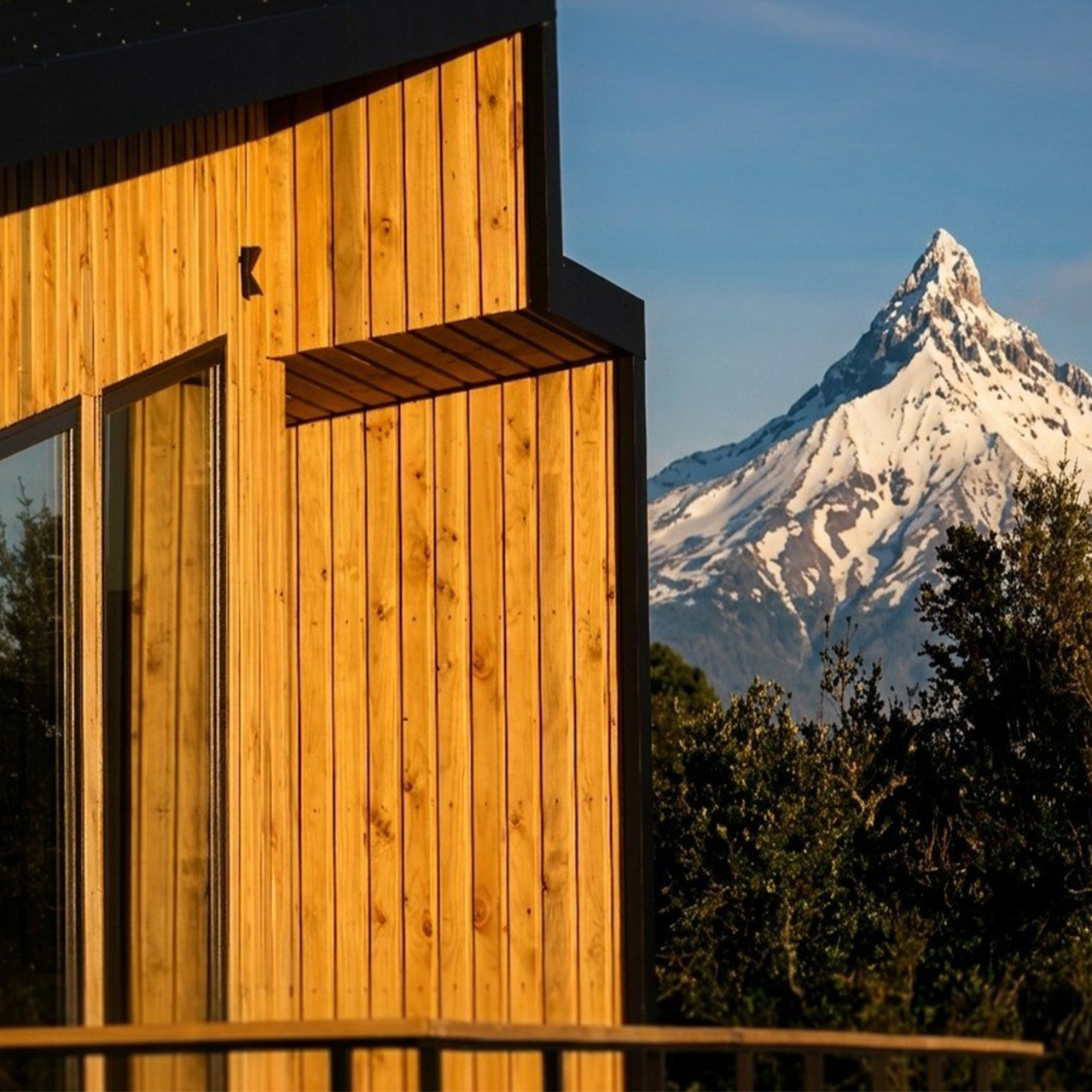 Pico afilado del volcán Puntiagudo junto a la fachada de madera de una suite